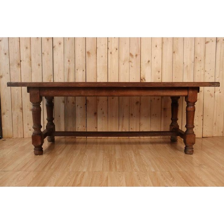 a large wooden table sitting on top of a hard wood floor next to a wall