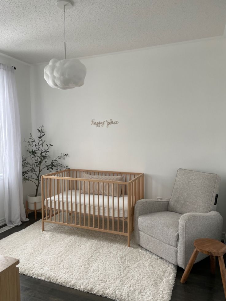 a baby's room with a chair, crib and rug in front of the window