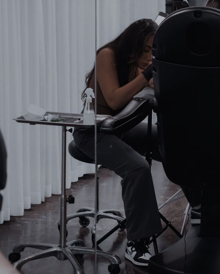 a woman is sitting in an office chair looking at her phone