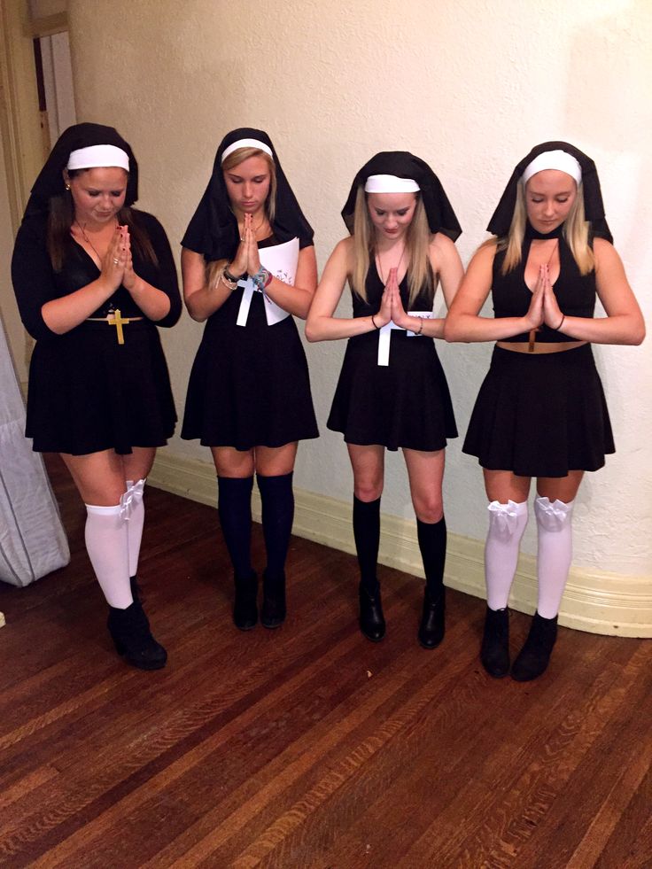 four girls dressed in black and white are standing together with their hands folded over their chests