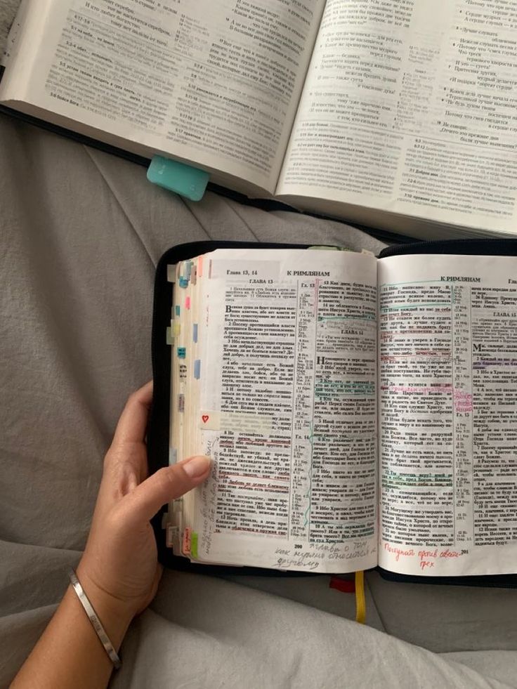 an open bible being held by a woman's hand on top of a bed