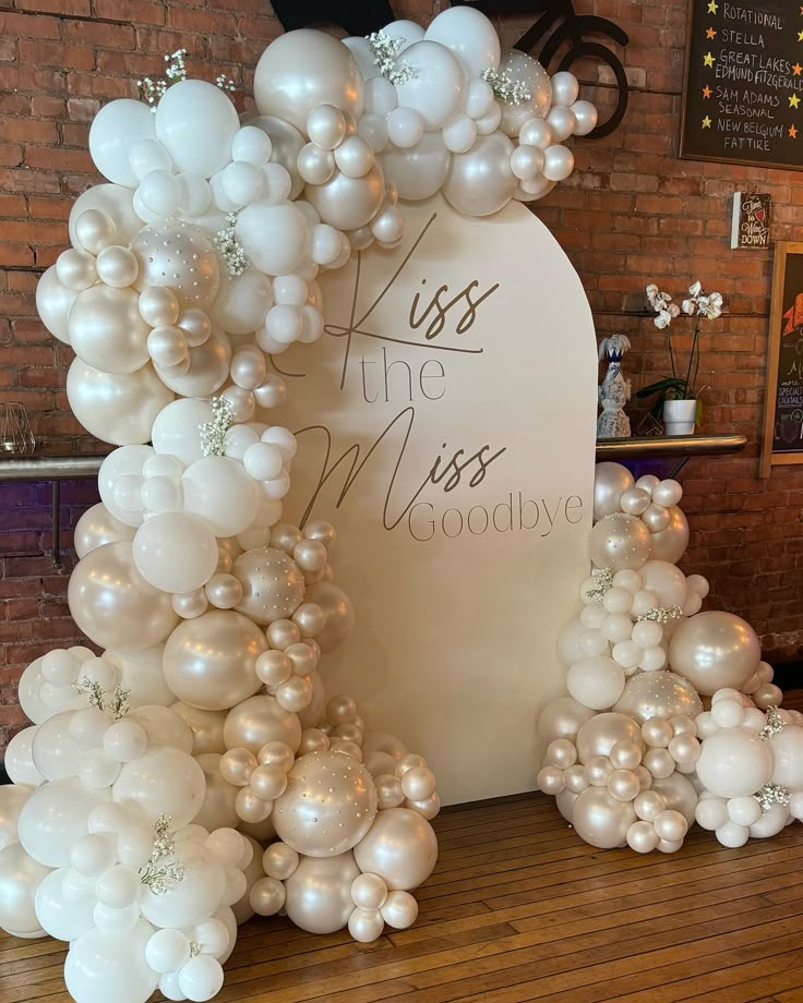 balloons are arranged in the shape of an arch with words on it and white flowers