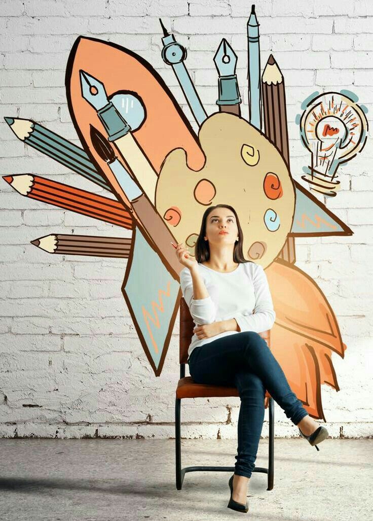 a woman sitting on a chair in front of a brick wall with an artistic mural behind her