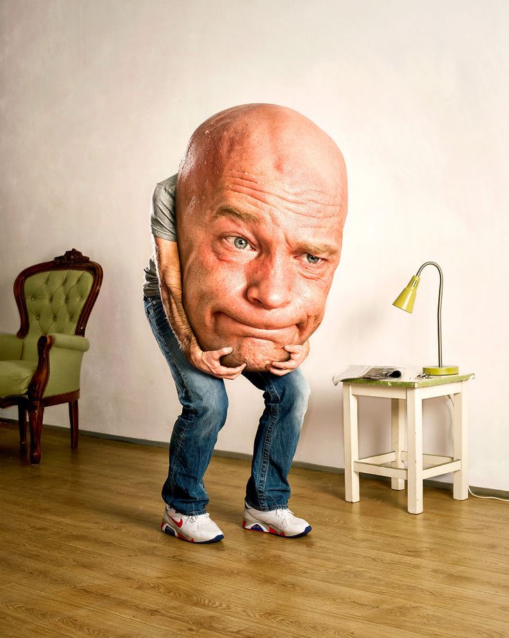 a man is standing in front of a chair with a giant head on it