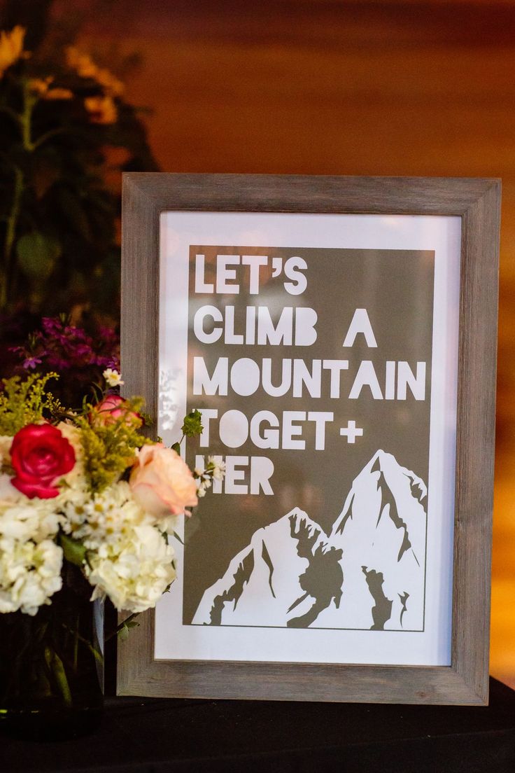 there is a sign that says let's climb a mountain together and flowers are in front of it