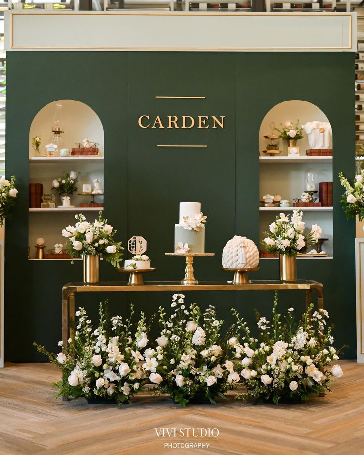 the cake table is decorated with flowers and greenery