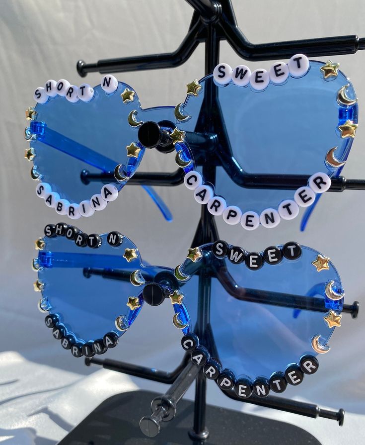 two heart shaped sunglasses with words written on them, attached to a black metal stand