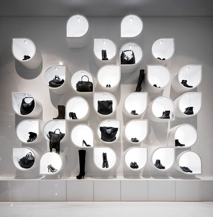 a display in a store filled with lots of white shelves and black shoes on top of each shelf