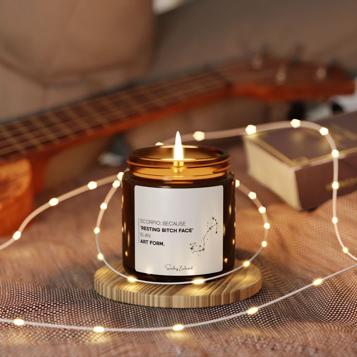 a candle sitting on top of a wooden table next to a string of lights and a guitar