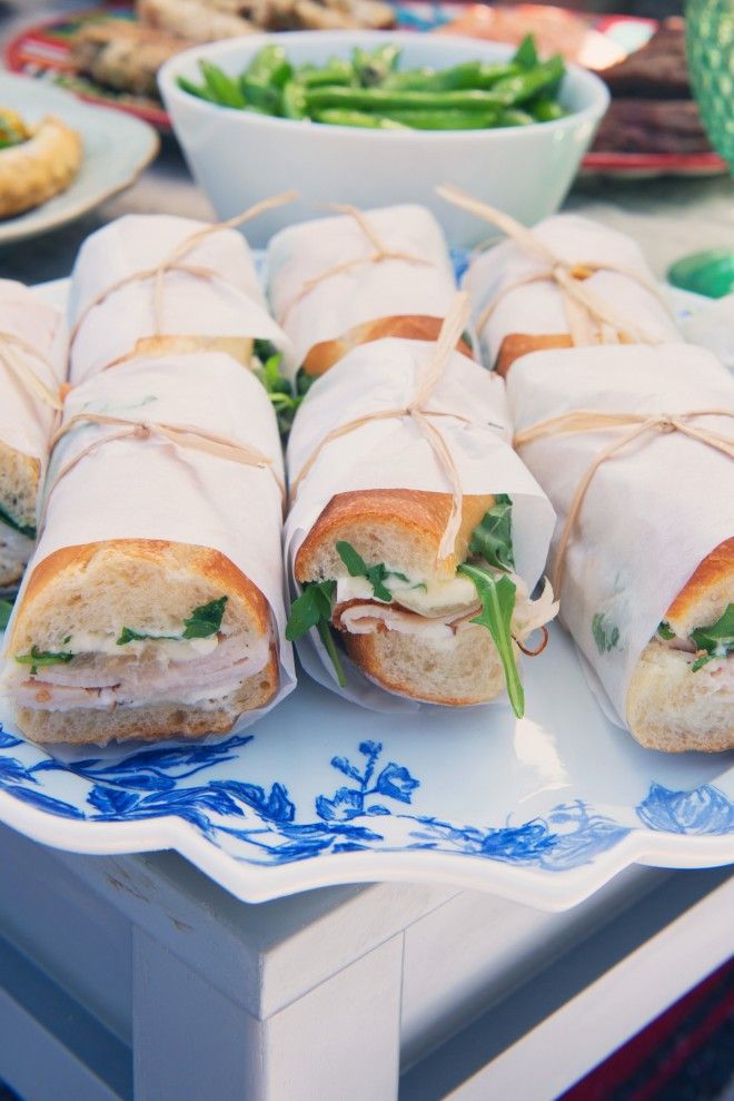 several sandwiches wrapped in white paper on a blue and white plate