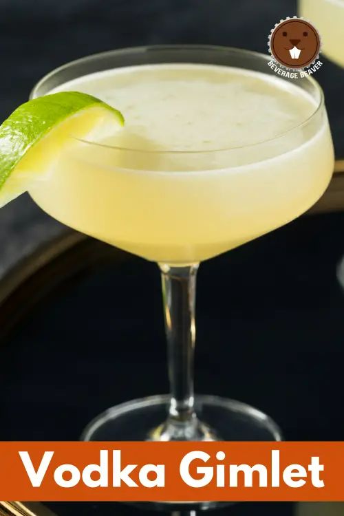 two cocktails sitting on top of a table next to each other with lime garnish