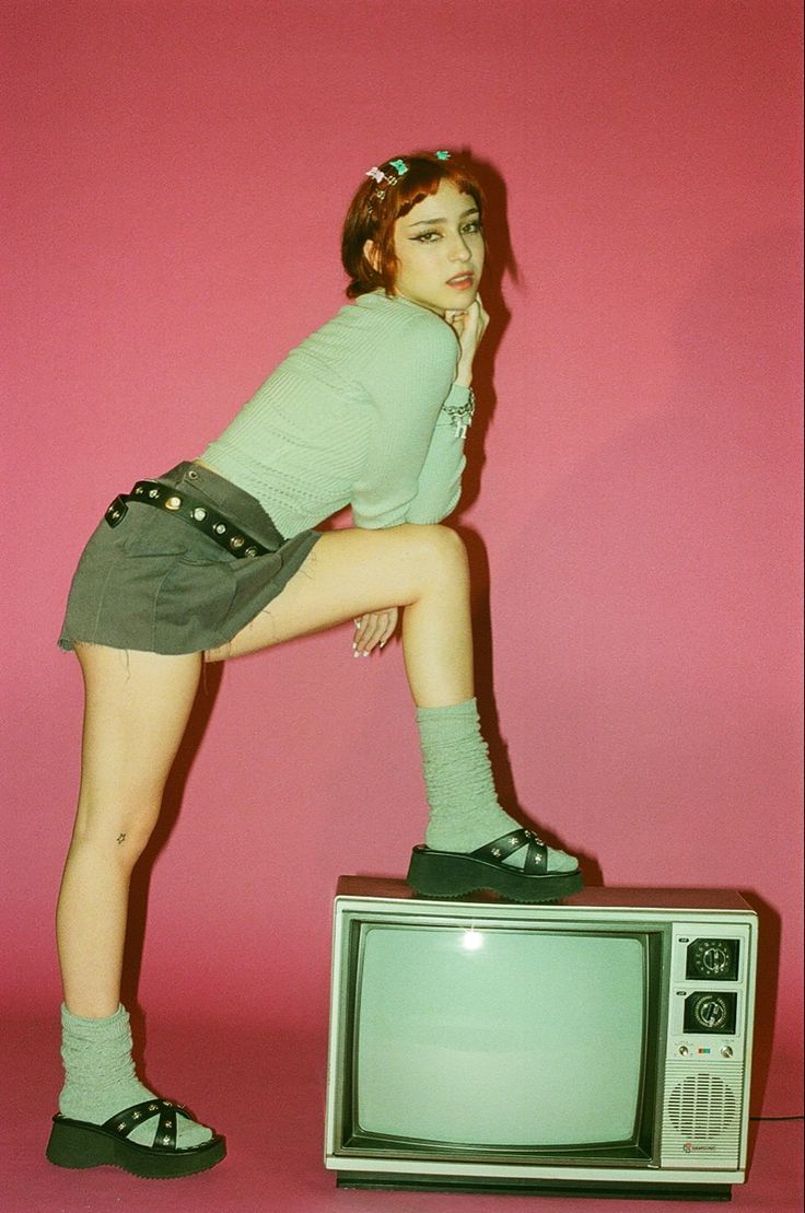 a woman leaning on top of an old tv