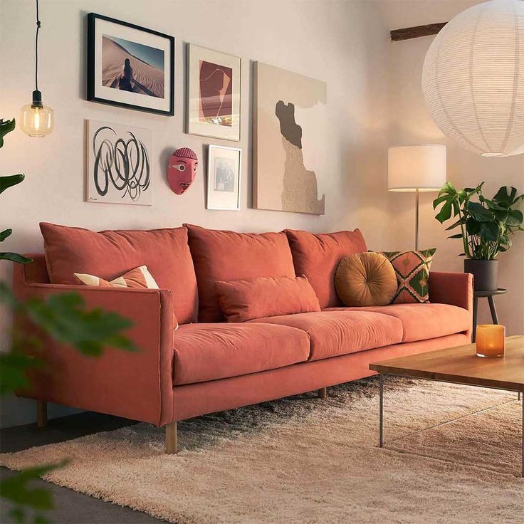 a living room with orange couches and pictures on the wall above it's coffee table