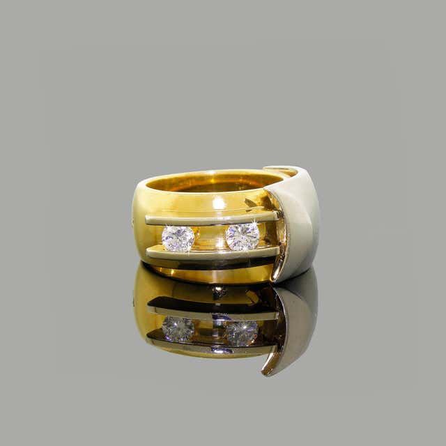 a gold and white ring with three diamonds on it's side, sitting on a reflective surface