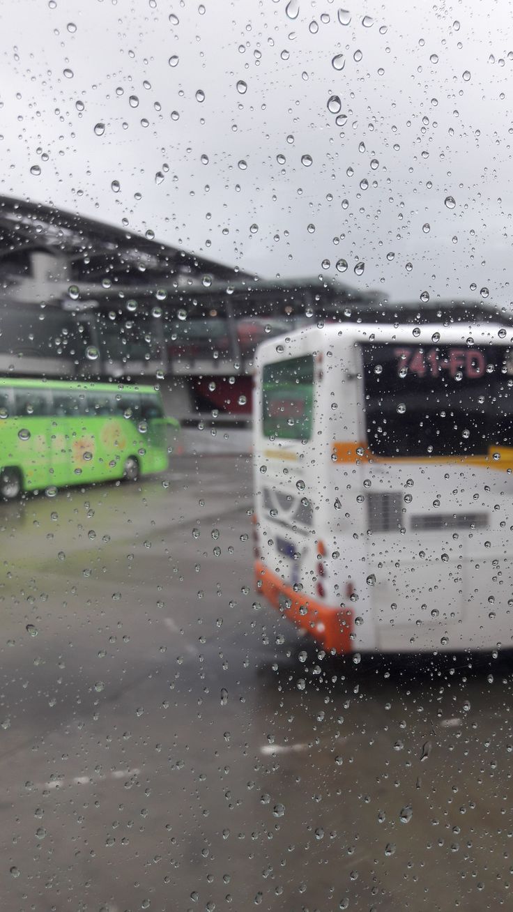 the bus is driving down the road in the rain outside, with other buses behind it