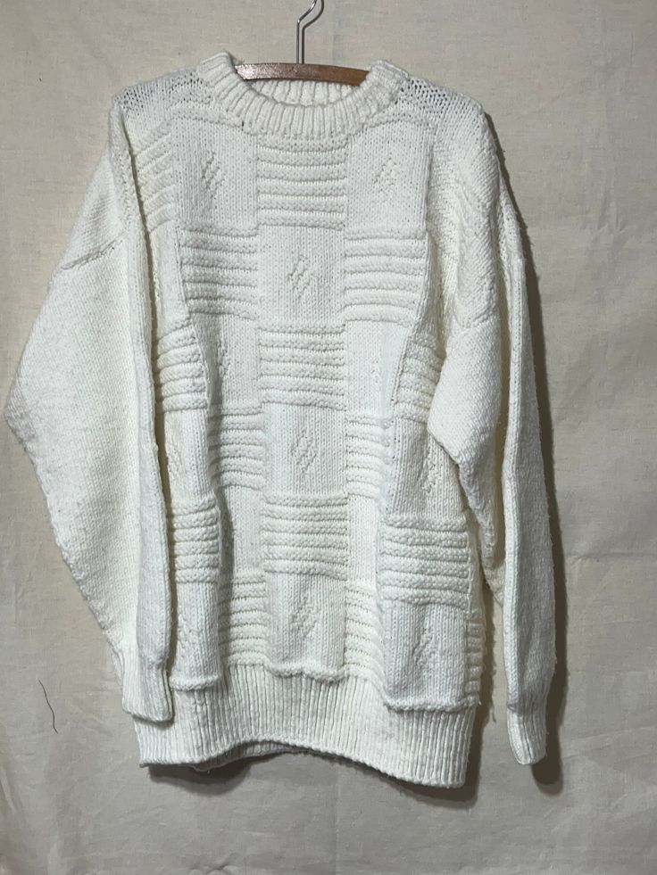 an old white sweater hanging on a clothes hanger, with the top half turned down