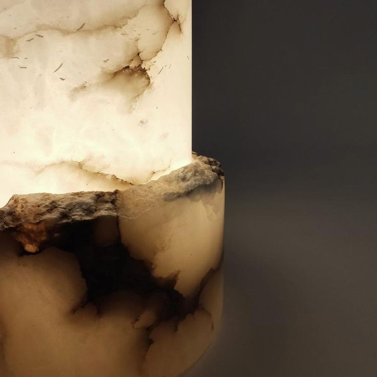 a close up of a white marble vase on a table with a black and gray background