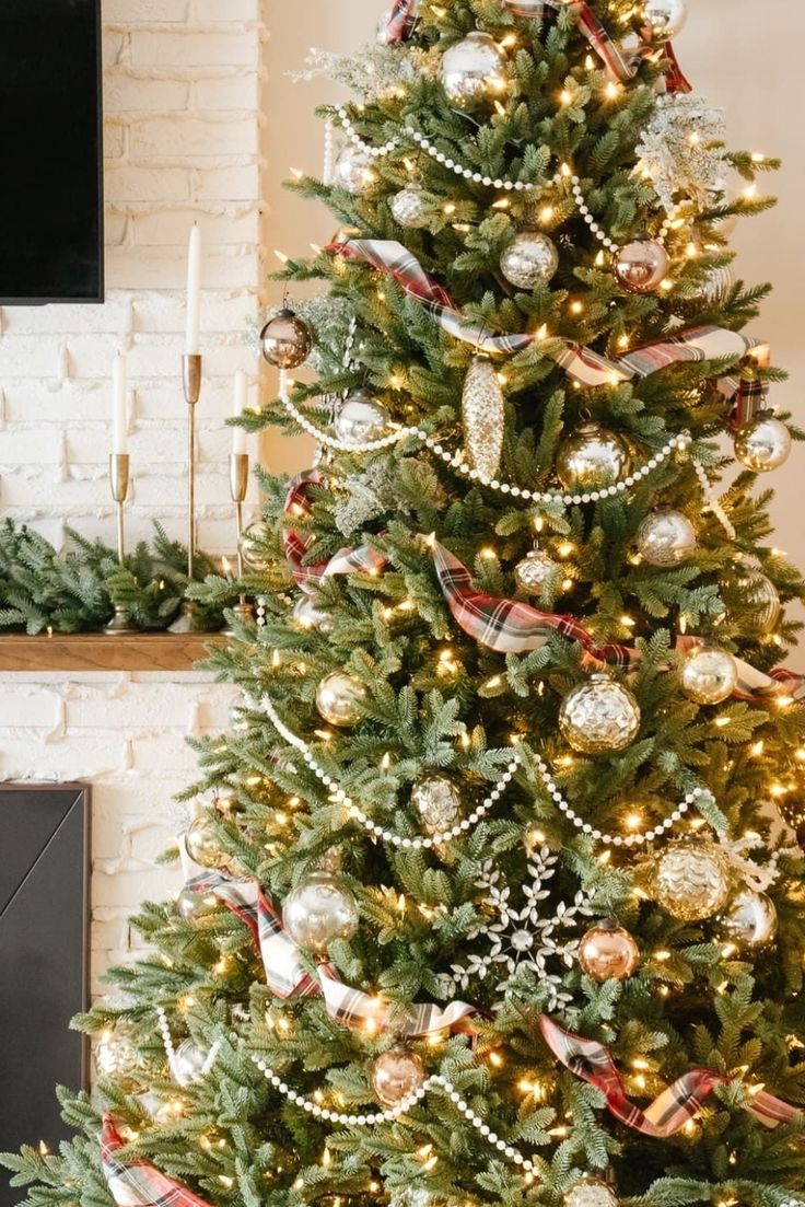 a decorated christmas tree in front of a fireplace