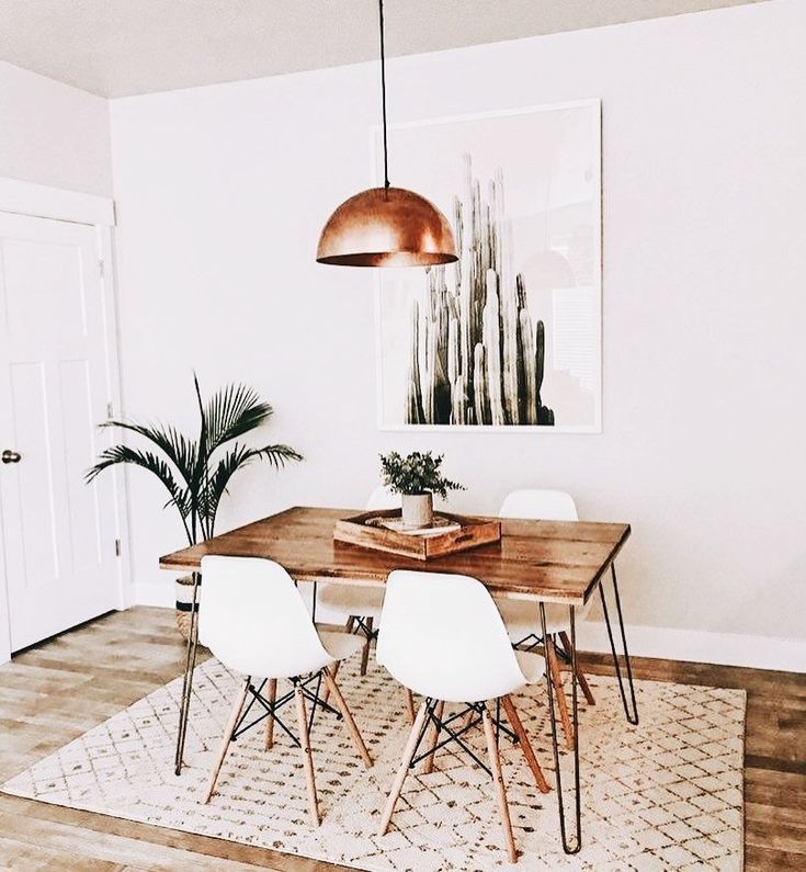 a dining room table with white chairs and a potted plant in the corner next to it