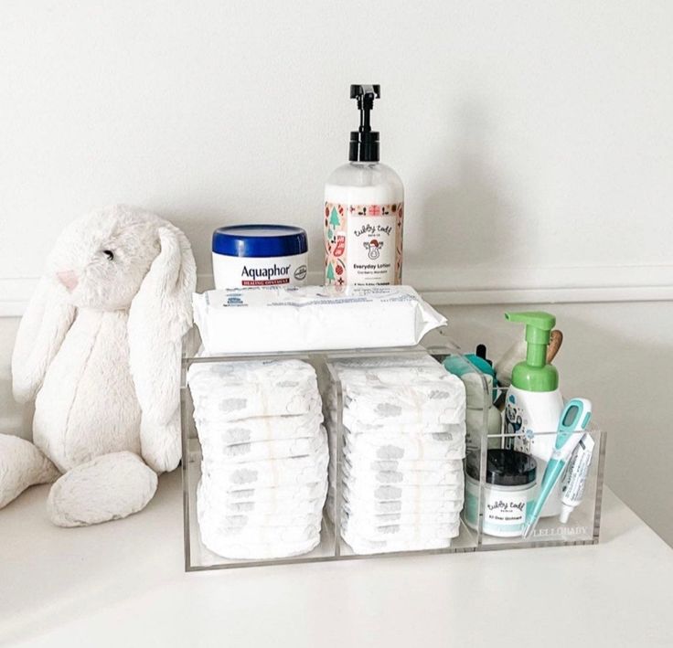 a white teddy bear sitting on top of a counter next to toiletries and soaps