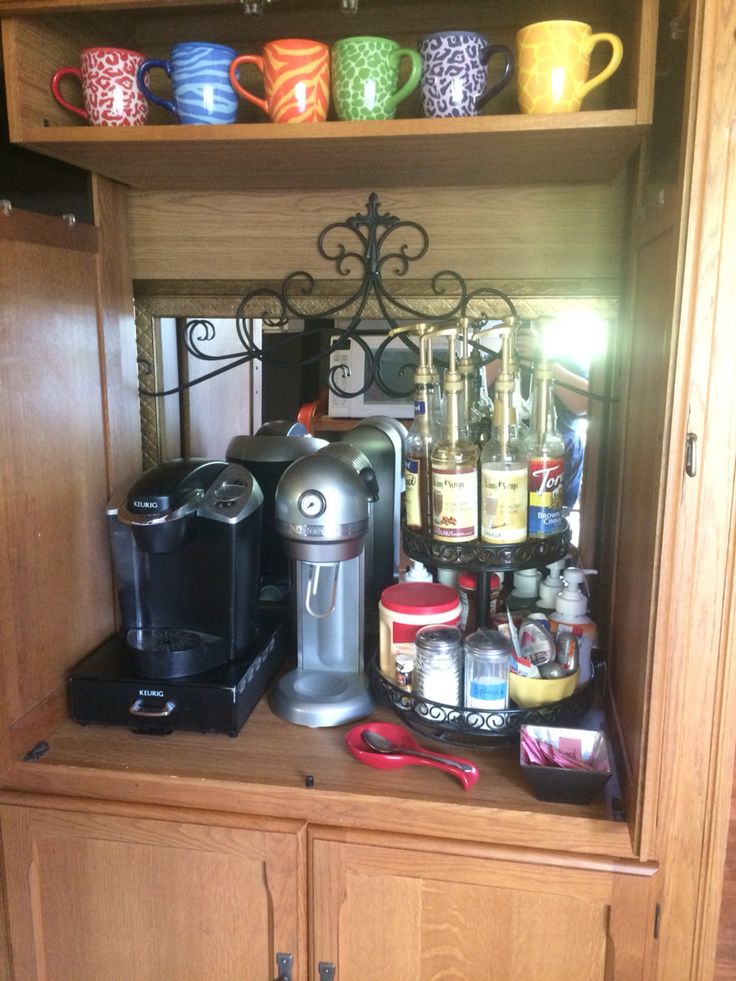 there is a coffee maker and cups on the shelf in this kitchen cabinet with many other items