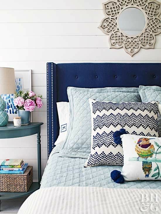 a bed with blue headboard and pillows on it