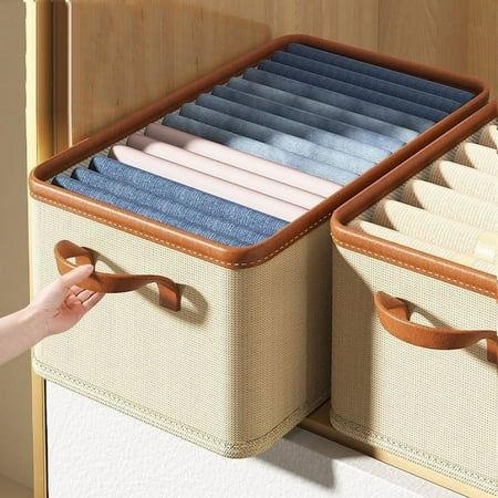 two suitcases that are open with clothes hanging on the handles and one has a hand reaching for it