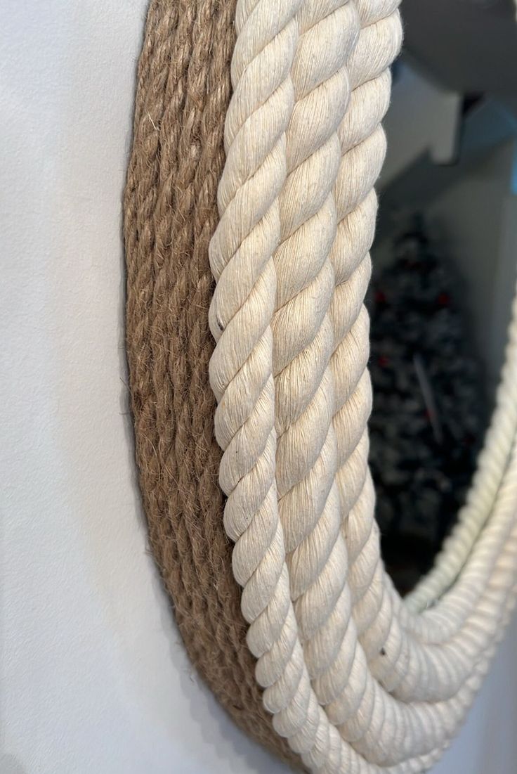 a rope mirror hanging on the side of a wall