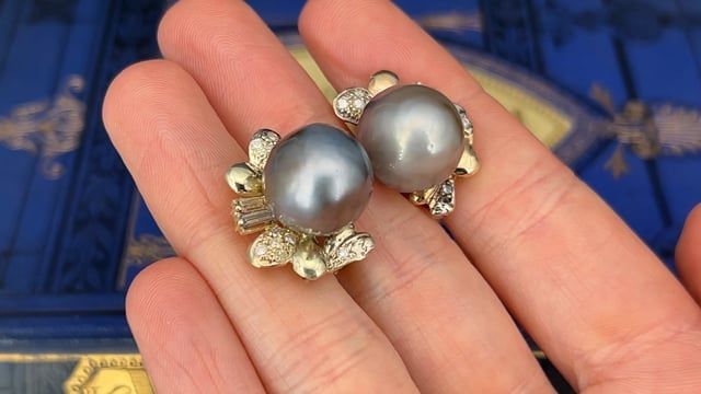 These gorgeous pearl earrings are each accented with one (1), post set, cultured Tahitian pearl, eleven (11), bead set, round brilliant cut diamonds and two (2), prong set, baguette cut diamonds. The earrings measure 22.8mm X 17.3mm. The earrings are finished with hinged omega backs for pierced ears. One of the baguette diamonds is unnoticeably chipped. Tahitian Pearl Jewelry With Diamond Accents For Wedding, Tahitian Pearl Jewelry With Matching Earrings For Anniversary, Classic Tahitian Pearl Earrings For Anniversary, Elegant Tahitian Pearl Earrings For Anniversary, Elegant Tahitian Pearl Earrings For Wedding, Elegant Tahitian Pearl Jewelry For Anniversary, Tahitian Pearl Round Earrings For Wedding, Round Tahitian Pearl Earrings For Wedding, Luxury Tahitian Pearl Earrings For Anniversary