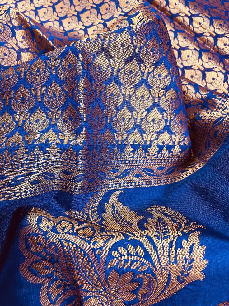 Gorgeous Statement designer Saree in Royal Blue color with Muted Gold Zari Weaving. Saree has Floral Motifs all over with design pattern borders with big flower buttas. Item : Saree Color : Royal Blue Base Fabric : Banarasi Silk Blouse piece : Comes with Blouse piece Blouse material : Soft Banarasi Silk Work : Handloom Fall & Edging(Yes/No) : Yes Disclaimer: Slight variation in actual color vs. image is possible due to the screen resolution. Kindly note : Since this Saree is handmade hence littl Royal Blue Saree With Zari Weaving For Diwali, Royal Blue Saree For Puja And Diwali, Royal Blue Saree For Diwali Puja, Blue Traditional Wear With Zari Weaving In Raw Silk, Blue Raw Silk Blouse Piece With Traditional Patterns, Transitional Blue Banarasi Silk Blouse Piece, Blue Tussar Silk Lehenga With Traditional Patterns, Blue Art Silk Blouse Piece With Traditional Patterns, Blue Banarasi Silk Blouse For Transitional Season