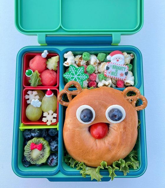 a bento box filled with fruit and veggies, including a reindeer face