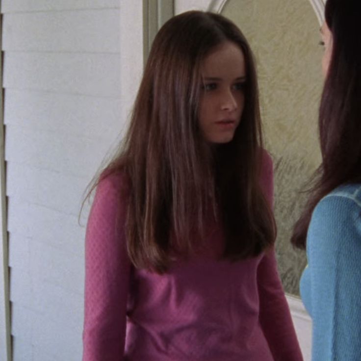 two girls standing in front of a mirror looking into each other's eyes,