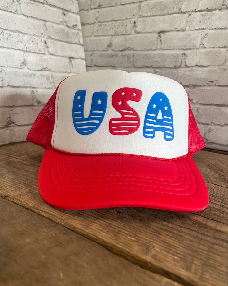 Custom USA Puff Print Youth Hat - Foam Hat with adjustable snapback Do your kids need gear for a USA celebration? We have you covered! This is the ultimate hat to sport during any USA occasion. With eight design choices to choose from, there is sure to be a hat for everyone in your kid group. The designs will be in the puff colors as shown (blue and red) in the "Design Options" pictures, but you can customize your hat by picking a hat color.  **If you would like a design to have different wording, or the colors to be different, please message us and we will try our best to accommodate you! ** Listing Reference: OTTO Cap 5 Panel High Crown Polyester Foam Front Mesh Back Trucker Hat This hat is 100% polyester and has a 5 panel seamless foam front panel with a lining matching braid.  Plastic Patriotic Adjustable Hat For Independence Day, Fun Red Adjustable Bucket Hat, Patriotic Adjustable Trucker Hat For 4th Of July, Red Baseball Cap For 4th Of July, 4th Of July Snapback Baseball Cap, 4th Of July White Adjustable Baseball Cap, White Adjustable Baseball Cap For 4th Of July, Adjustable White Baseball Cap For 4th Of July, Adjustable White Hat For 4th Of July