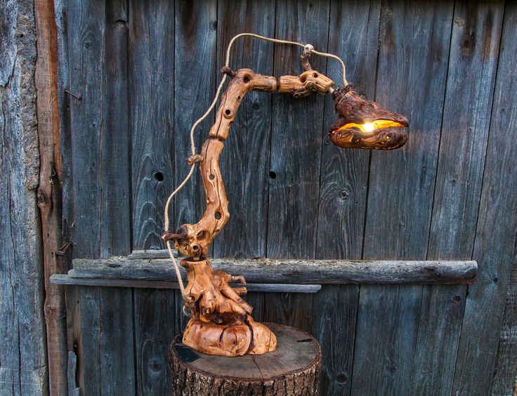 a lamp that is on top of a tree stump in front of a wooden fence