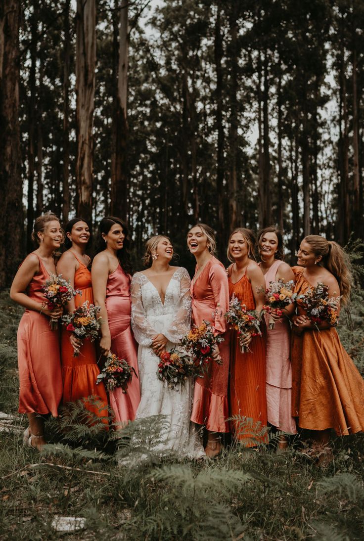 a group of women standing next to each other in front of some trees and grass