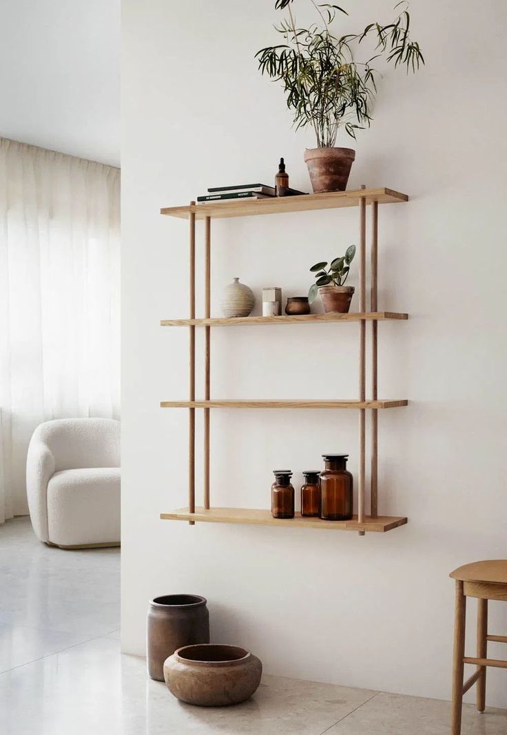 two shelves with plants and vases on them in a white room next to a window