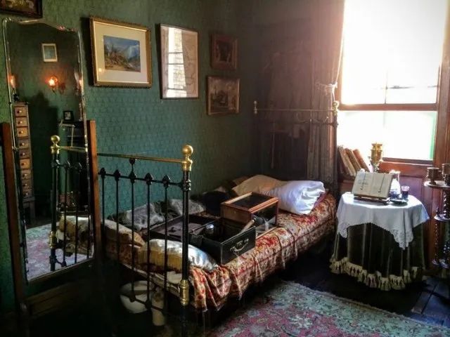 an old fashioned bedroom with green walls and antique furniture, including a metal bed frame