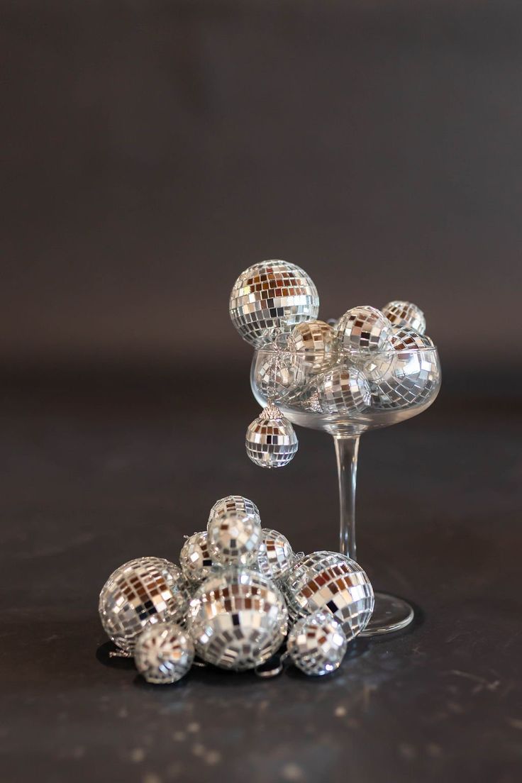 a wine glass filled with lots of disco balls on top of a table in front of a dark background