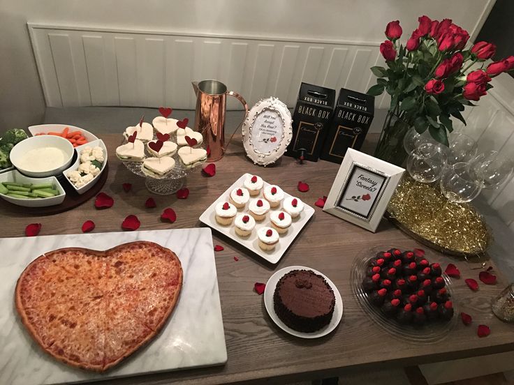 a table topped with cakes and desserts next to vases filled with red roses