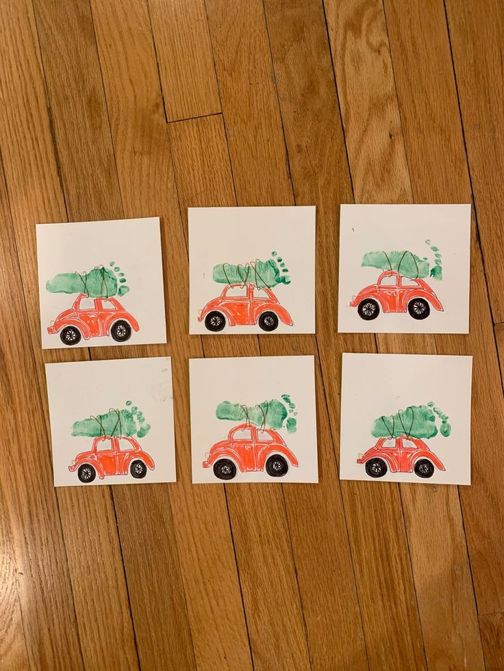 four pieces of paper with pictures of cars and trees on them sitting on a wooden floor