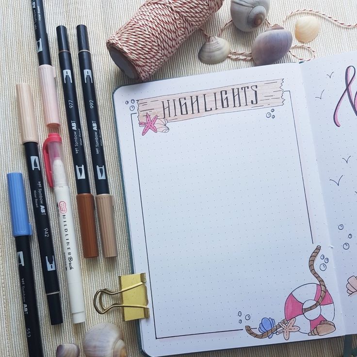 an open notebook sitting on top of a table next to some pens and pencils