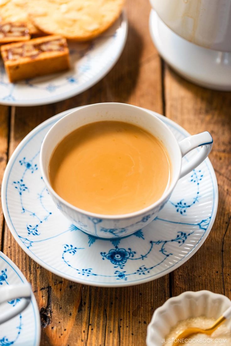 a cup of coffee on a saucer next to some crackers and other food