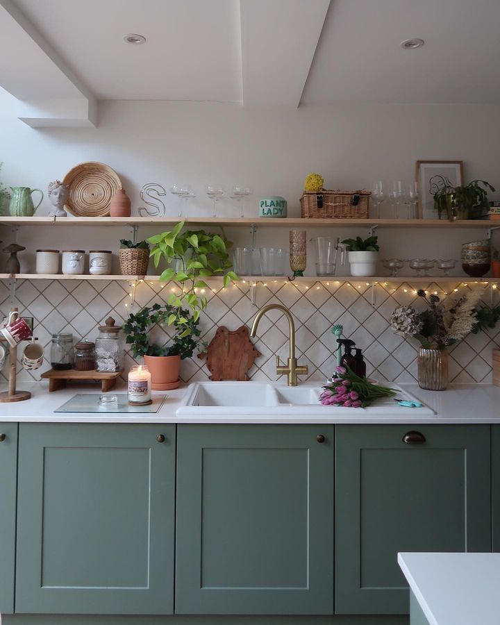 a kitchen filled with lots of green cupboards and counter top space next to a sink