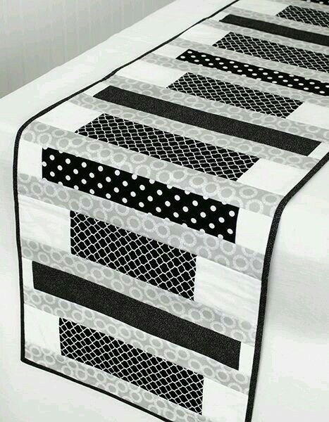 a black and white quilted table runner on top of a bed with polka dots