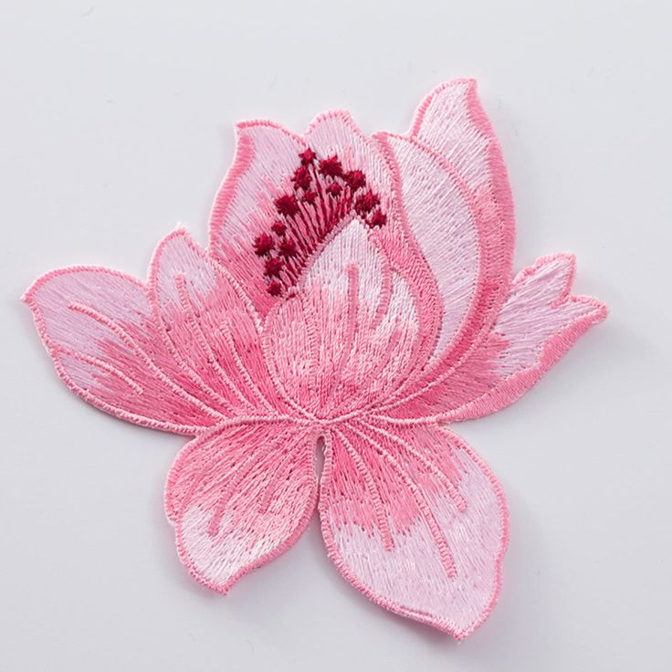 a pink flower is shown on a white surface with red threadwork in the center