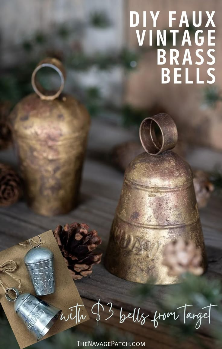 two brass bells sitting on top of a wooden table next to pine cones and evergreen needles