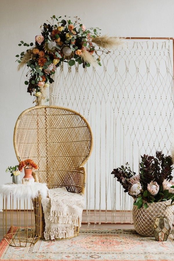 two wicker chairs sitting next to each other in front of a wall with flowers on it