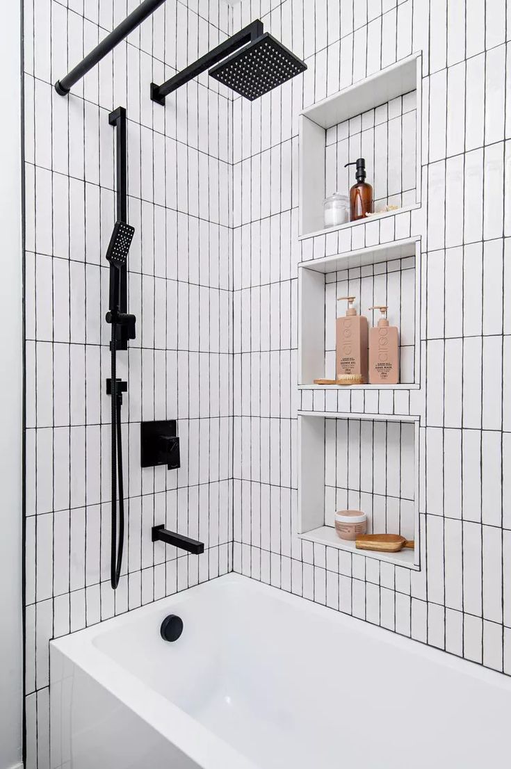 a white bath tub sitting next to a black and white tiled shower head in a bathroom