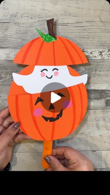 someone is cutting out a paper pumpkin with a large smile on it's face