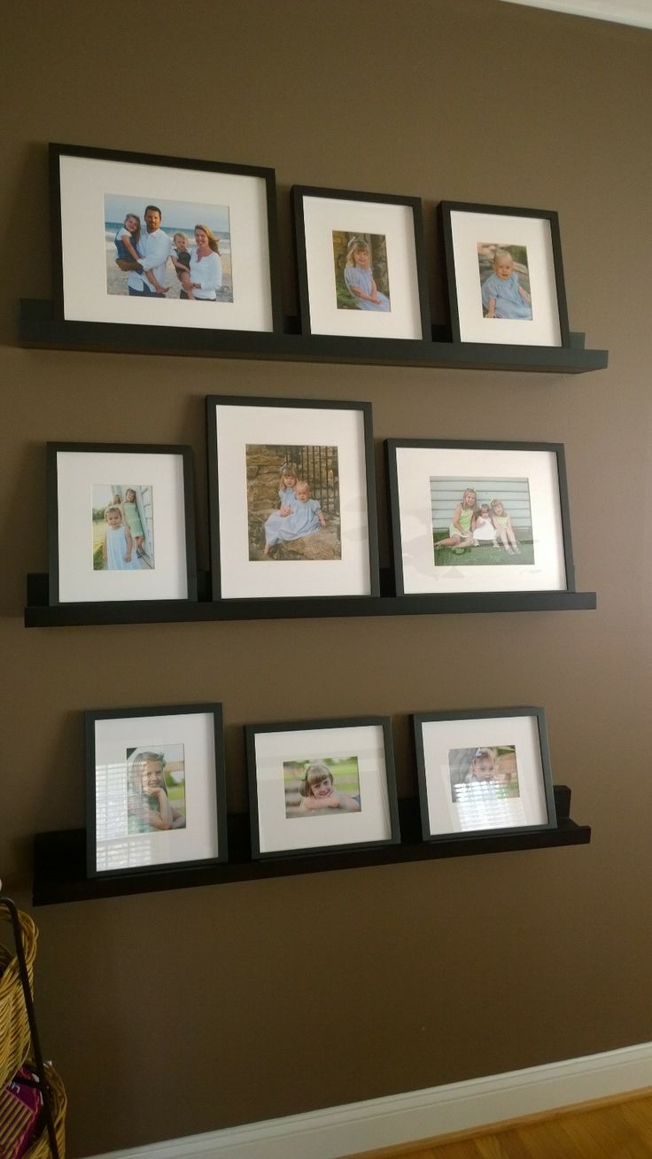 several black and white frames are hanging on the wall above a shelf with four pictures